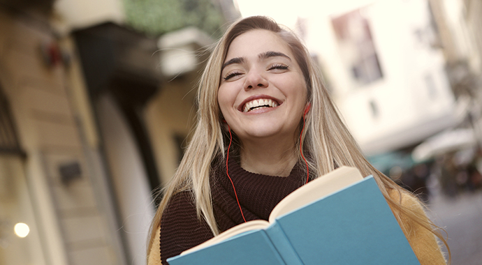 En kvinna blundar och ler stort samtidigt som hon håller en bok i händerna