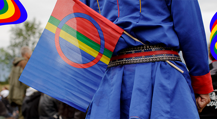 En mann i samisk kofte og med samisk flagg