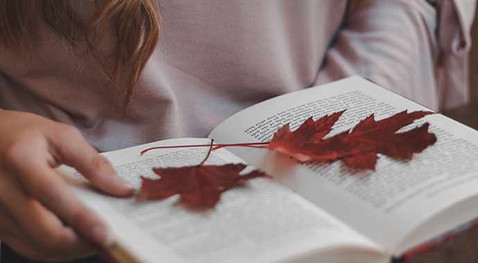 Bild på en uppslagen bok med två röda löv som ligger på sidorna. 
